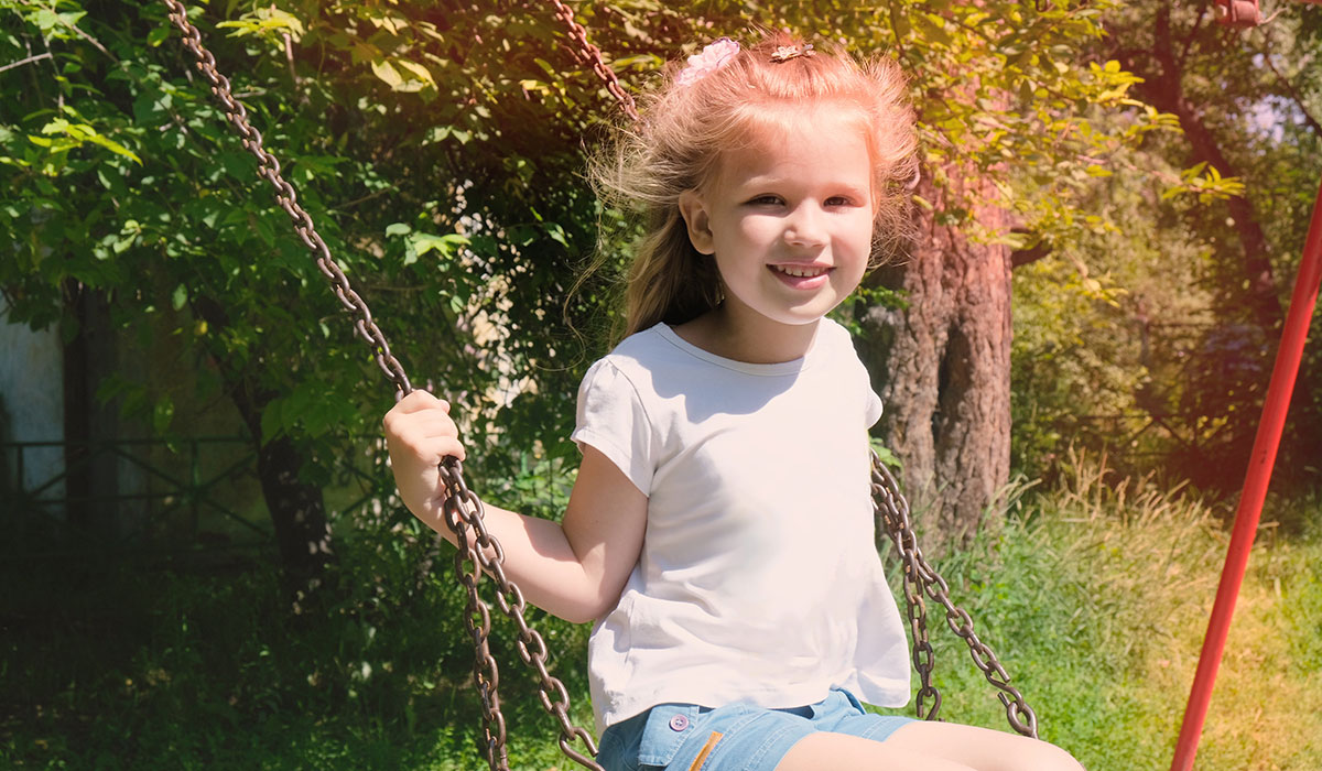 Happy child girl on swing, summer time. Life Events. Retro toned, Soft focus effect