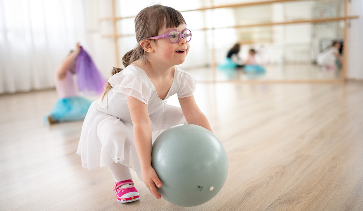 Little girl playing with ball at ballet class in dance studio. Concept of integration and education of disabled children.; Shutterstock ID 2204195333; purchase_order: -; job: -; client: -; other: