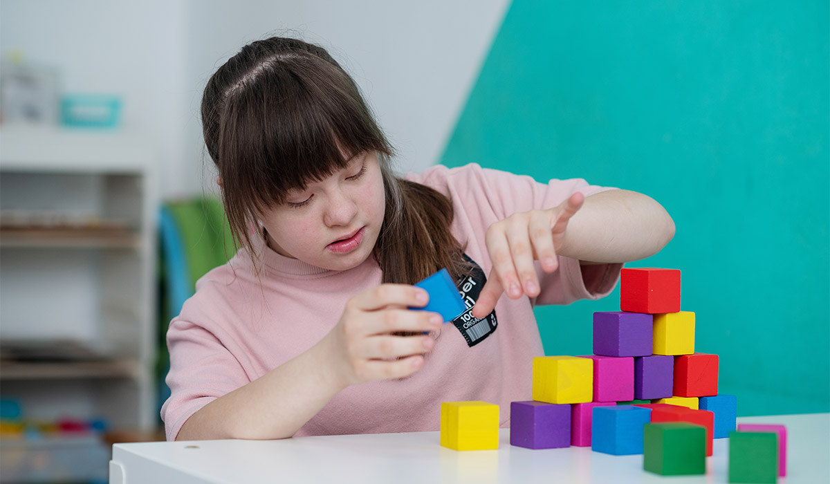 Sunny girl playing colored cubes in the educational room. World day of people with down syndrome. A special child; Shutterstock ID 2345803675; purchase_order: -; job: -; client: -; other: