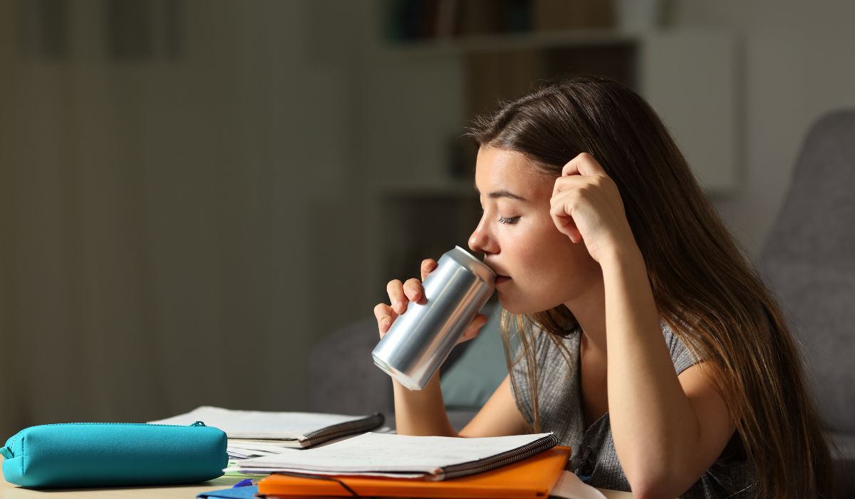 Teenager studying and drinking energy drink