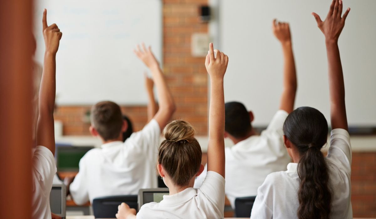 kids putting their hands up at school