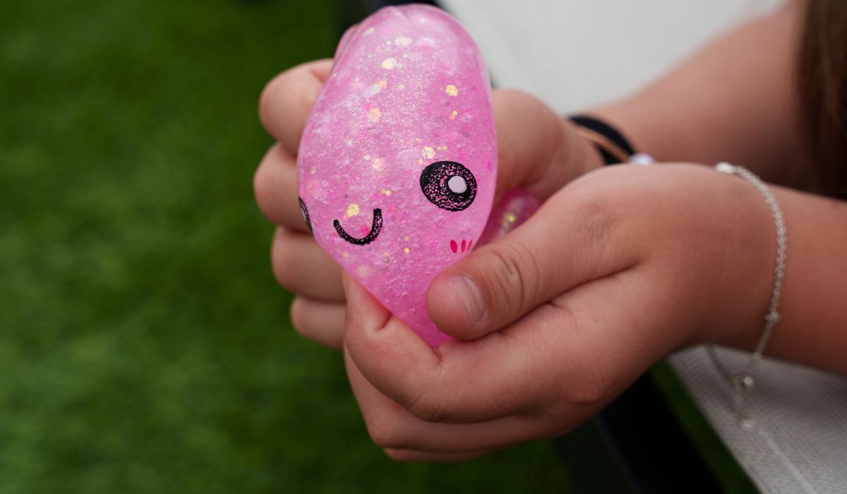 Child’s hand squeezing a pink glitter squishy dumpling toy