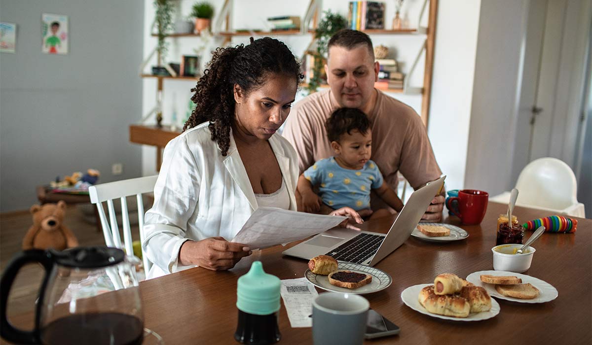 Stressed mom working from home while dad holds baby in background; Shutterstock ID 2624650045; purchase_order: -; job: -; client: -; other: