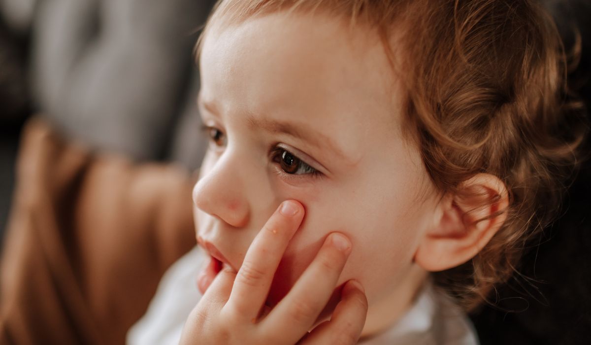 Toddler with hand over mouth