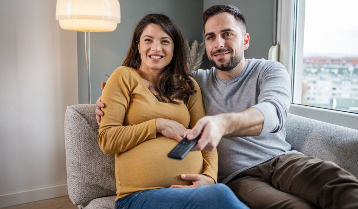 Pregnant woman and wife watching television