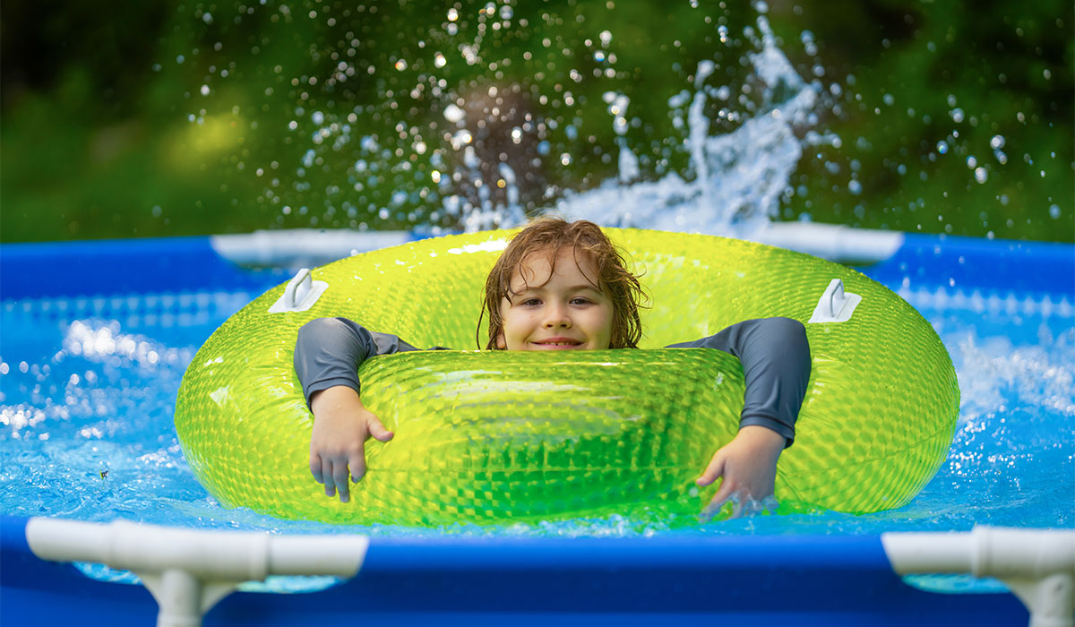 Kid playing in kids pool at home. Kids swim and splash in pool in garden backyard. Child swim in inflatable circle pool on summer sunny day outdoors on home yard. Kids swimming pool at home.; Shutterstock ID 2543046819; purchase_order: -; job: -; client: -; other: